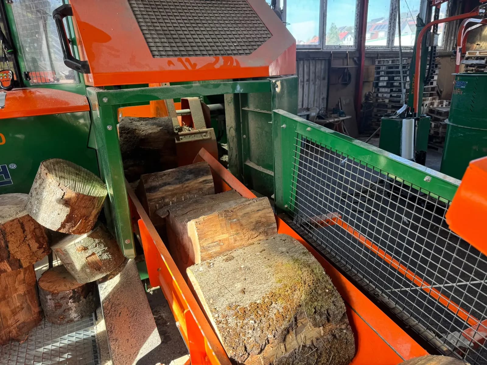 Stammabschnitte in der orangefarbenen Zuführung des Säge-Spalt-Automaten