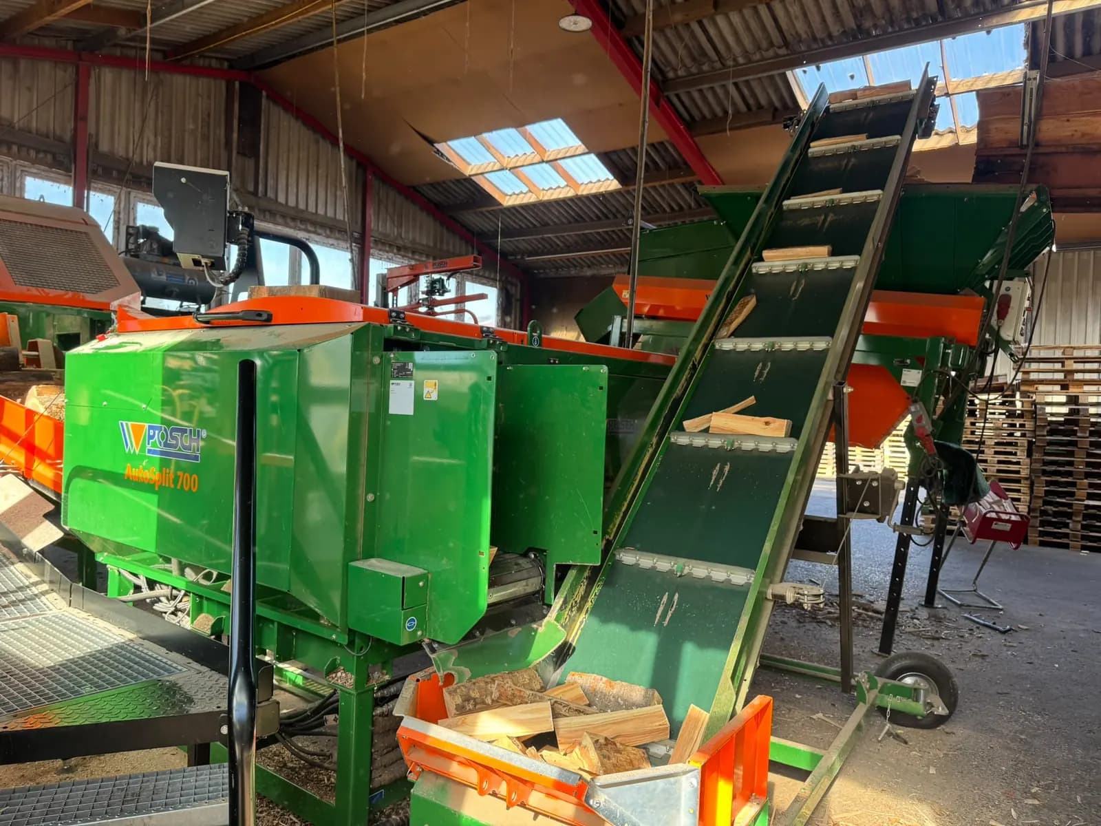 Posch-Spaltautomat mit Steigförderband, auf dem frisch gespaltene Buchenscheite nach oben laufen